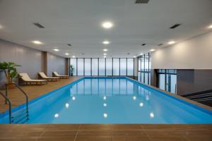 a swimming pool in a hotel lobby with chairs and tables at Pine Astoria Hotel in Tbilisi City