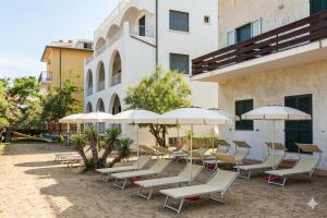 a group of chairs and umbrellas in front of a building at Hotel Villa Furia in Bellaria-Igea Marina