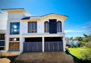 a large white house with a garage at Everfreshhighviewcottage in Ooty
