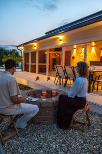 a man and a woman sitting on chairs around a fire pit at HelloHal Házak in Tiszafüred