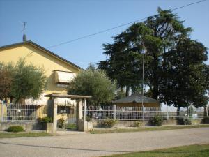 una casa gialla con una recinzione bianca e un albero di Camere Solidea a Veronella