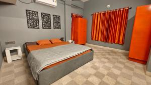 a bedroom with a bed and orange curtains at Casa pinto Valencia and The Second Storey in Mangalore