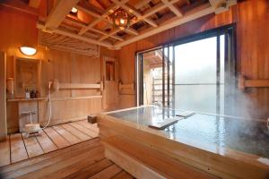 a large bathroom with a bath tub and a window at 24時間源泉かけ流しを ひとりじめできる 一棟貸しVilla安曇野 in Azumino