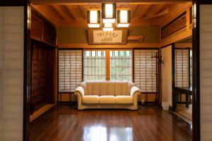 a living room with a couch in a room with windows at 24時間源泉かけ流しを ひとりじめできる 一棟貸しVilla安曇野 in Azumino
