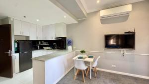 a kitchen with white cabinets and a small table with chairs at The Ancestry Suites in Wasig