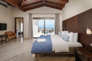 a bedroom with a bed with a view of the ocean at Porto Galini Seaside Resort & Spa in Nikiana +109 photos