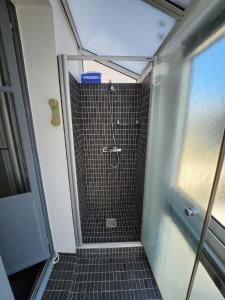 a bathroom with a shower with black tile at Chambre avec vue sur mer in Saint Malo