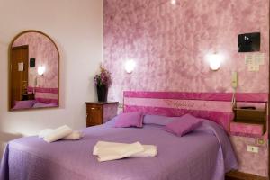 una camera da letto con un letto viola e due asciugamani di Hotel Ristorante Supersonik ad Acri