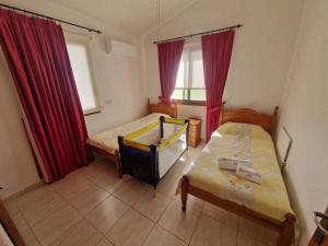 a small bedroom with two beds and red curtains at Marmario Villa 10 in Anarita