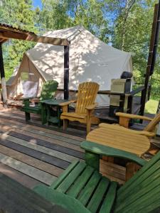 a wooden deck with chairs and a tent at Glamping Štôla- Symbioza in Vyšné Hágy