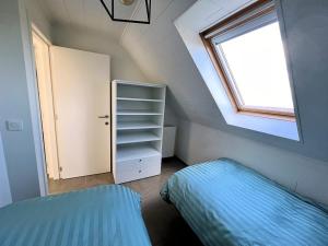 a attic bedroom with a bed and a window at Hof ter Eversam in Alveringem