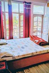 a bed in a room with windows and a bedspread at Harmony Homestay Couple & Family friendly prime location Easy access to Mall Rd -City view in Solan