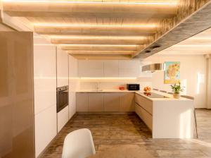 a kitchen with white cabinets and a wooden ceiling at Iseo Lake Luxury Duplex - Centro & Design in Iseo