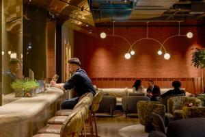 a man sitting at a bar in a restaurant at The Cloud One Frankfurt-Metropolitan in Frankfurt