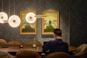 a man sitting at a table with a laptop in a restaurant at The Cloud One Frankfurt-Metropolitan in Frankfurt