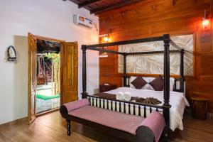 a bedroom with a canopy bed with a pink bench at Thanima Farm Life Pvt Ltd in Nallepilli