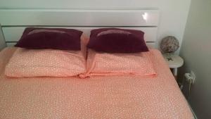 a bed with two purple pillows on top of it at Chambre double 30km de la Tour Eiffel in Saint-Michel-sur-Orge