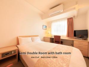 a bedroom with a bed and a desk with a television at Hotel Famy Inn Kinshicho in Tokyo