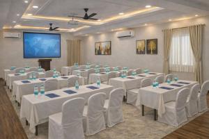 a conference room with white tables and chairs and a screen at Grand Maalyasa Hotel and Suites, US Consulate Hyderabad 2 Mins walk in Hyderabad