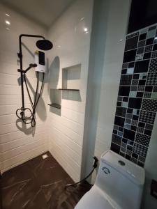 a bathroom with a toilet and a tile wall at Nua Tone Riverside in Thalang +2 photos