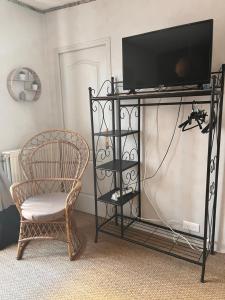 a tv stand with a chair and a television on it at Les Fleurs in Monpazier