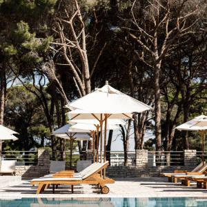 a group of chairs and umbrellas next to a pool at Falkensteiner Hotel Adriana l Adults Only in Zadar +25 photos