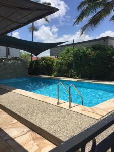 a swimming pool with an umbrella next to it at Country Plaza Motor Inn in Mackay