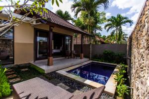 a villa with a swimming pool in front of a house at Villa Mandi Resort & spa in Ubud