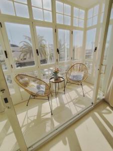 two chairs and a table in a room with windows at Estudio Puerto de Sotogrande in Sotogrande