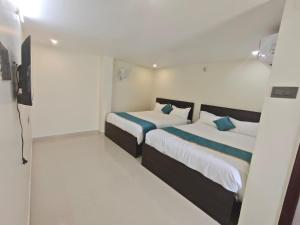 two beds in a room with white walls and blue pillows at HOTEL VAJRA Grand in Tirupati