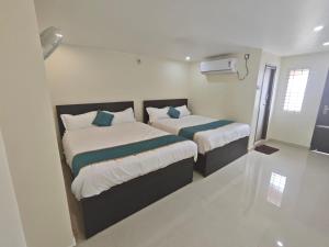 two beds in a small room with white walls at HOTEL VAJRA Grand in Tirupati