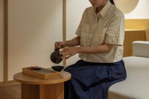 a woman sitting on a bed playing with a table at Anook Ryokan Hotel Daejeon Daeheung in Daejeon