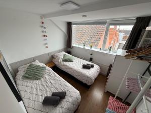a small room with two beds and a window at Maisonnette Indysenne in Zandvoort