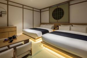a bedroom with two beds and a table and chairs at Anook Ryokan Hotel Daejeon Daeheung in Daejeon +159 photos