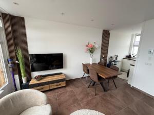 a living room with a table and a tv at Maisonnette Indysenne in Zandvoort