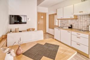 a kitchen with white cabinets and a wooden floor at byRosi Apartments in Parcines