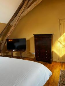 a bedroom with a bed and a dresser with a television at La maison des romans du Château du Sollier - Charme Calme Confort Climatisation - à 5mn du péage de Bourges à la campagne - stationnement privé -Panette Collection in Bourges