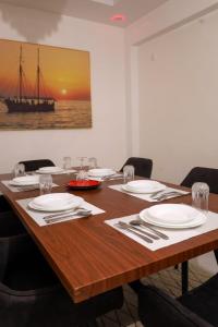 a wooden table with white plates and silverware on it at C Waves Palm Terraces in Mombasa