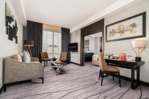 a living room with a couch and a desk in a room at Grand Swiss-Belhotel Darmo in Surabaya