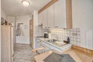 a kitchen with white cabinets and a sink at byRosi Apartments in Parcines +13 photos