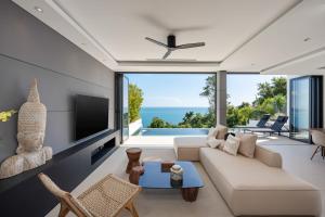 a living room with a white couch and a tv at Sukkho Samui Estates in Chaweng Noi Beach