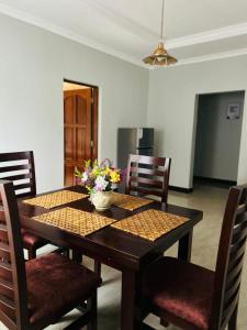 a dining room table with a vase of flowers on it at Olive homes in Nkunjila