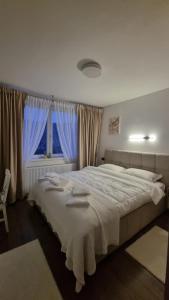 a bedroom with a large white bed and a window at Solovan Hill in Sighetu Marmaţiei