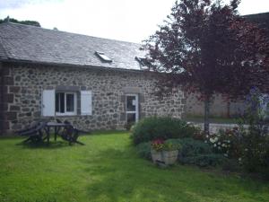 a stone house with a bench in the yard at Ferme de Lamourio in Saint-Cernin