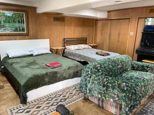 a room with two beds and a chair and a couch at Flower Avenue Hosting -Two DB Beds & Shower - Ground Floor Bedroom 1 Person 66 Night, 2 persons 122 - 3rd & 4th add 52 each in Silver Spring