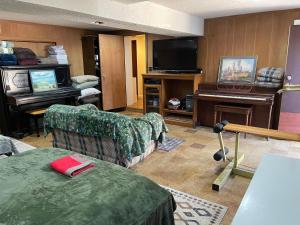 a living room with a tv and a couch and a piano at Flower Avenue Hosting -Two DB Beds & Shower - Ground Floor Bedroom 1 Person 66 Night, 2 persons 122 - 3rd & 4th add 52 each in Silver Spring