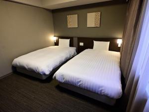 two beds in a hotel room with white sheets at Dormy Inn Hakata Gion in Fukuoka +70 photos