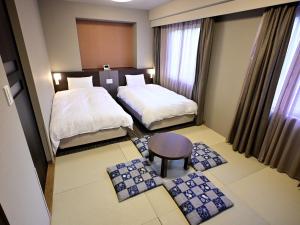 a hotel room with two beds and a table at Dormy Inn Hakata Gion in Fukuoka