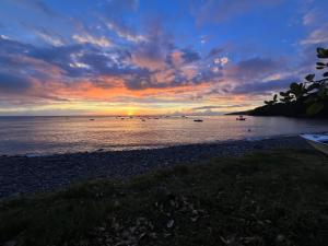 a sunset on a beach with boats in the water at Séjour Caraïbe in Pointe-Noire