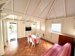 a room with a table and chairs and a tv at Séjour Caraïbe in Pointe-Noire